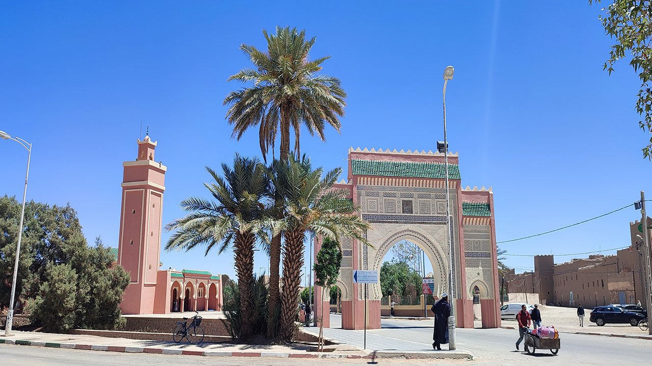  Rissani town center with ornate gate and palm trees.