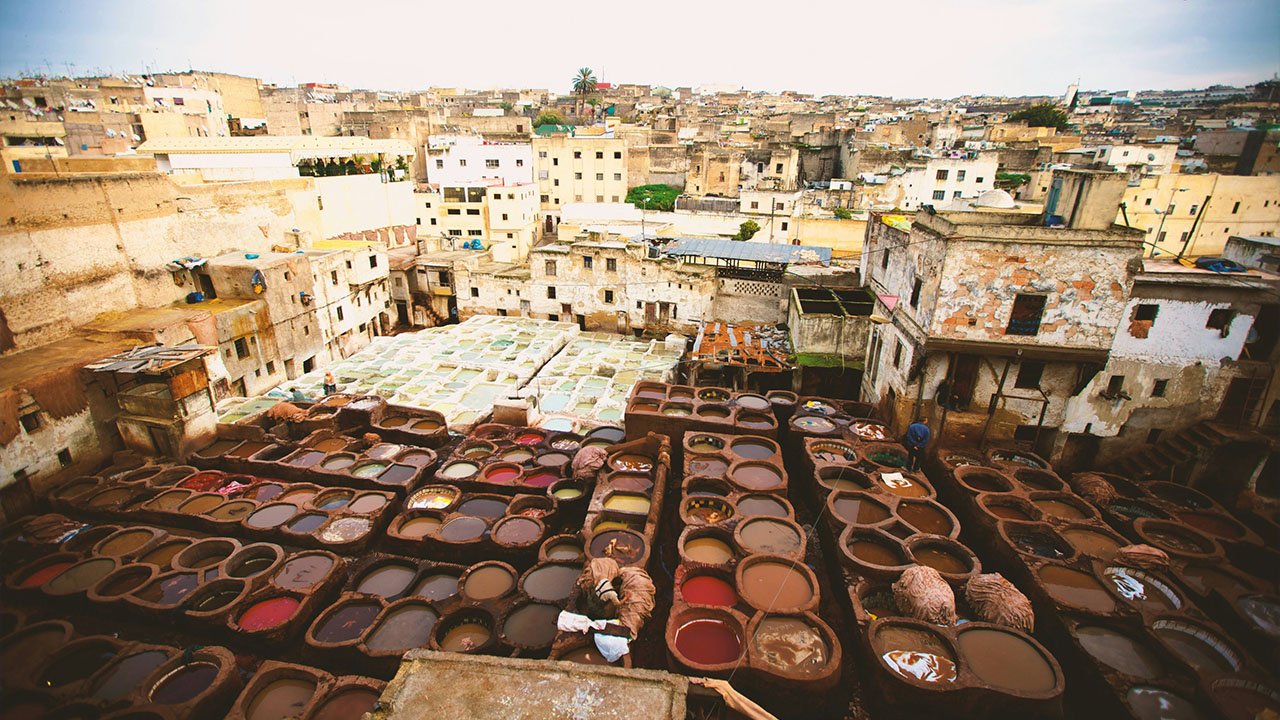 Ancient Fez tanneries amidst a dense, historical Moroccan cityscape.