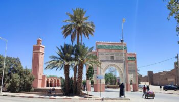 Rissani town center with ornate gate and palm trees.